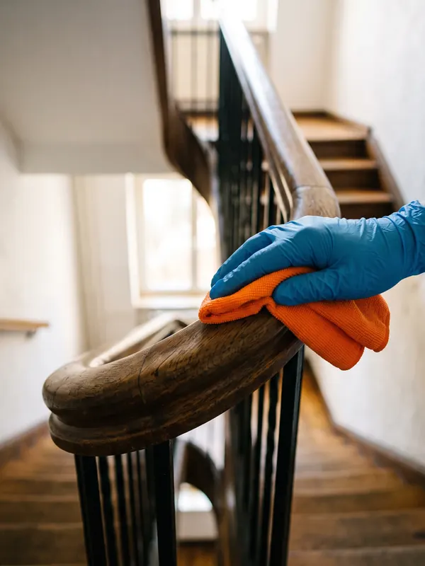 Handlauf im Treppenhaus wird mit Mikrofasertuch gereinigt